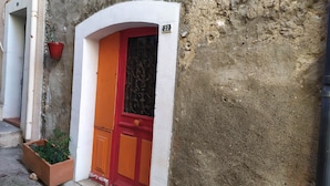 A building with a red door and a white archway. - Attractive, Renovated Village House in Traffic-free Street (Estagel)