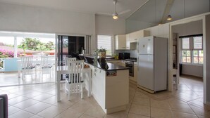 Een moderne keuken met witte kasten, een centraal eiland en een eethoek met witte stoelen.