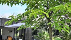 A patio with a table and chairs, surrounded by greenery and a wooden fence. - Seaside house (La Turballe)
