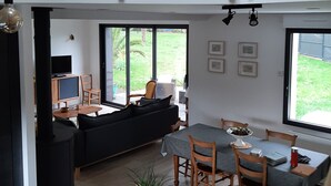 A modern multi-level living space with a dining area, sofa, and a TV in the lower level. - Seaside house (La Turballe)