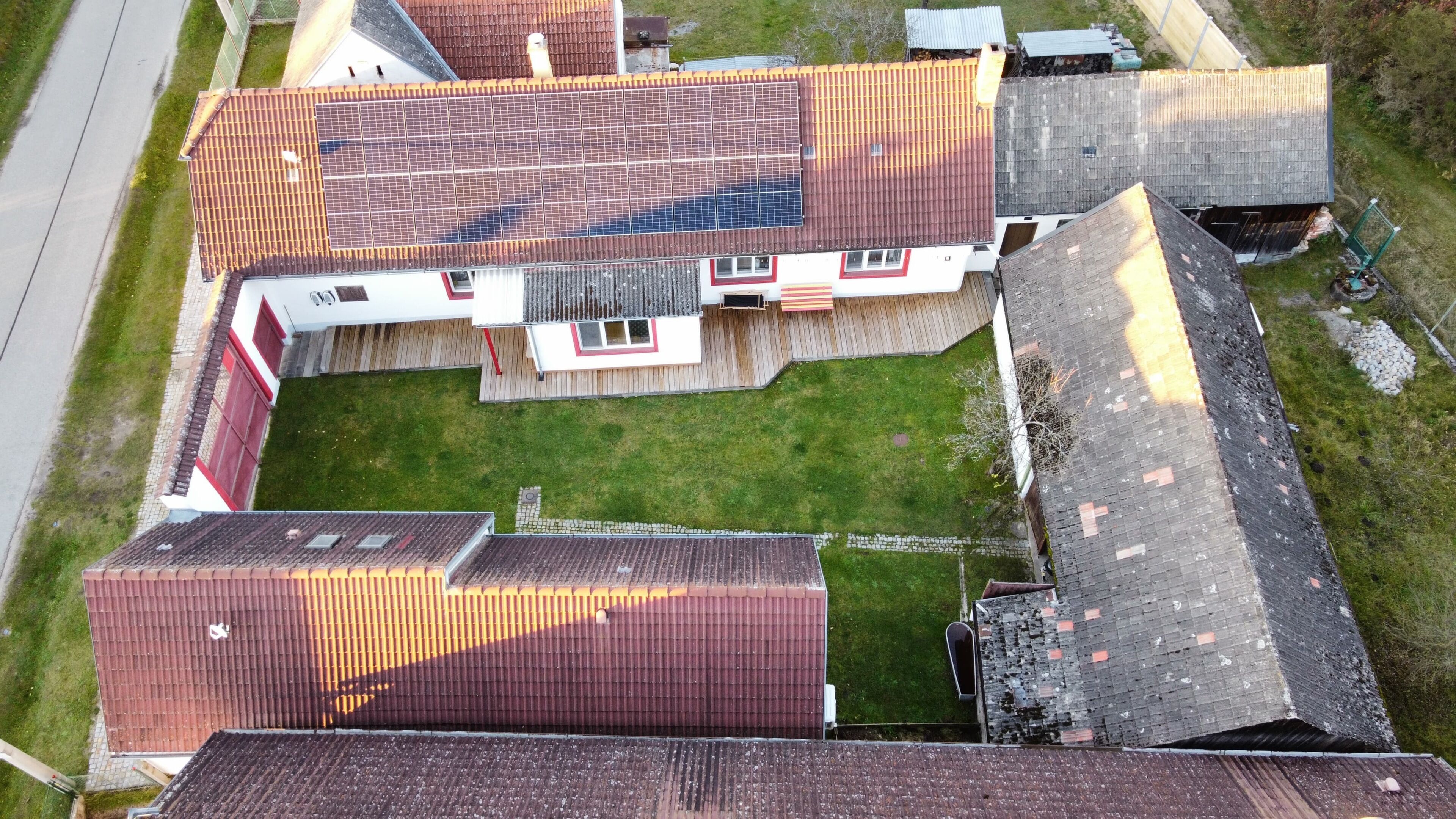 An aerial view of a residential area with multiple houses, each featuring distinct roof styles and a central grassy area.