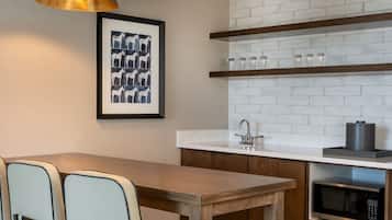 Une cuisine moderne avec un mur de fond en briques blanches, des armoires en bois, un four à micro-ondes en acier inoxydable et des luminaires suspendus.