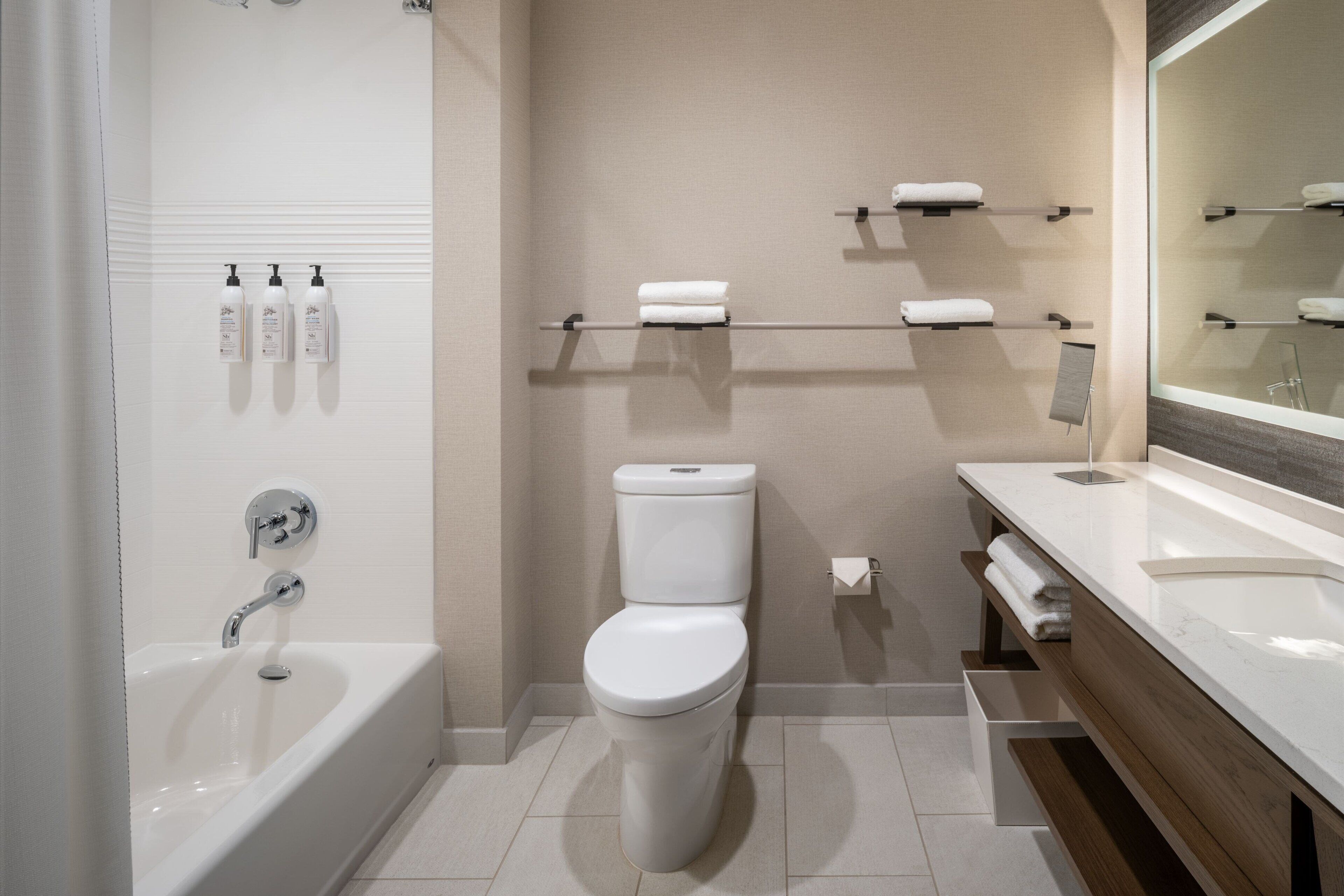 A modern bathroom with a bathtub, toilet, and vanity.