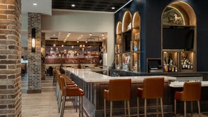 A bar area with a long counter, multiple stools, and a brick wall. - Delta Hotels by Marriott Wichita Falls Convention Center (Wichita Falls)