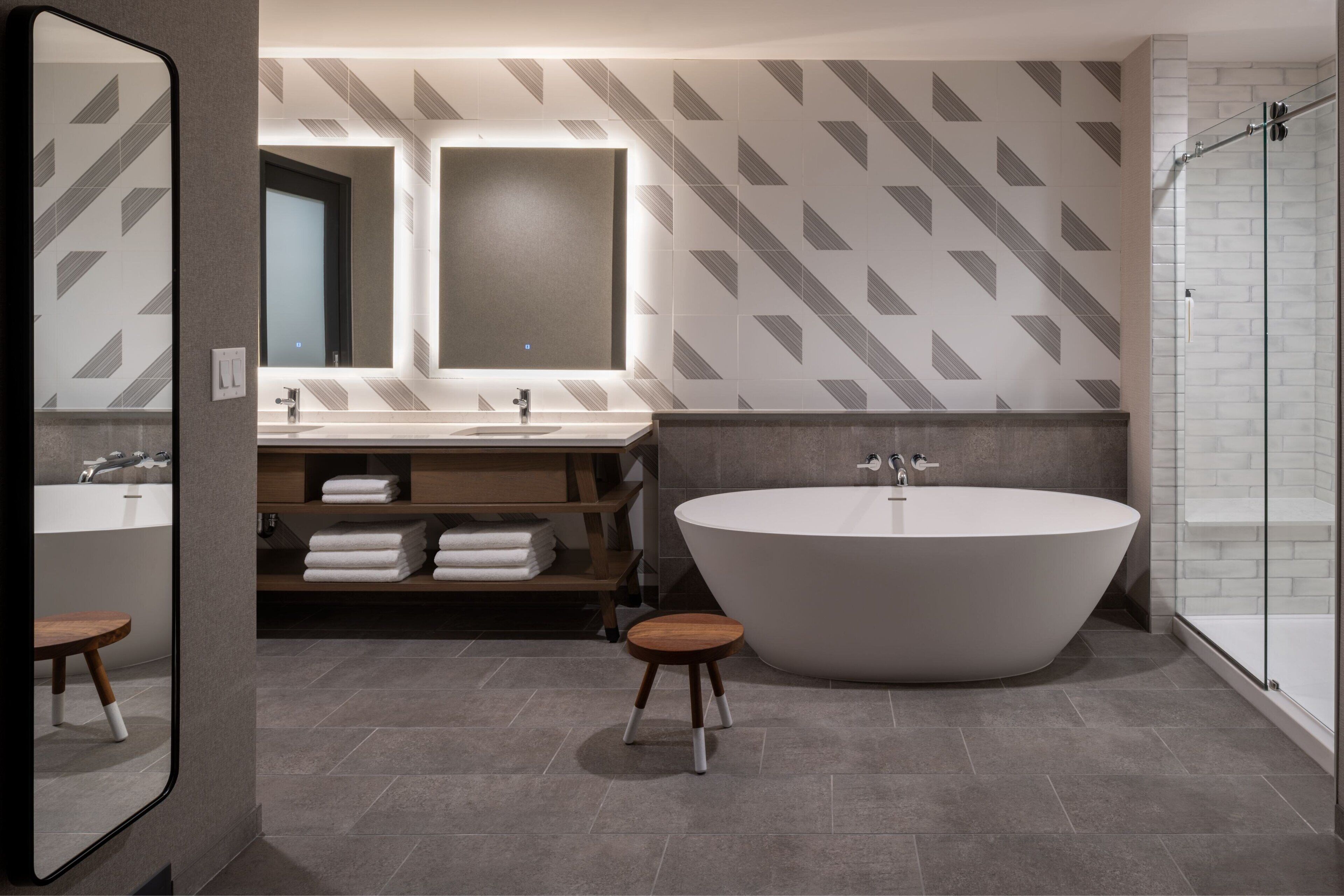 A modern bathroom with a freestanding bathtub, a vanity with a mirror, and a shower area.