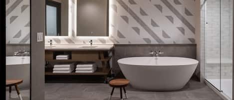 A modern bathroom with a freestanding bathtub, a vanity with a mirror, and a shower area.