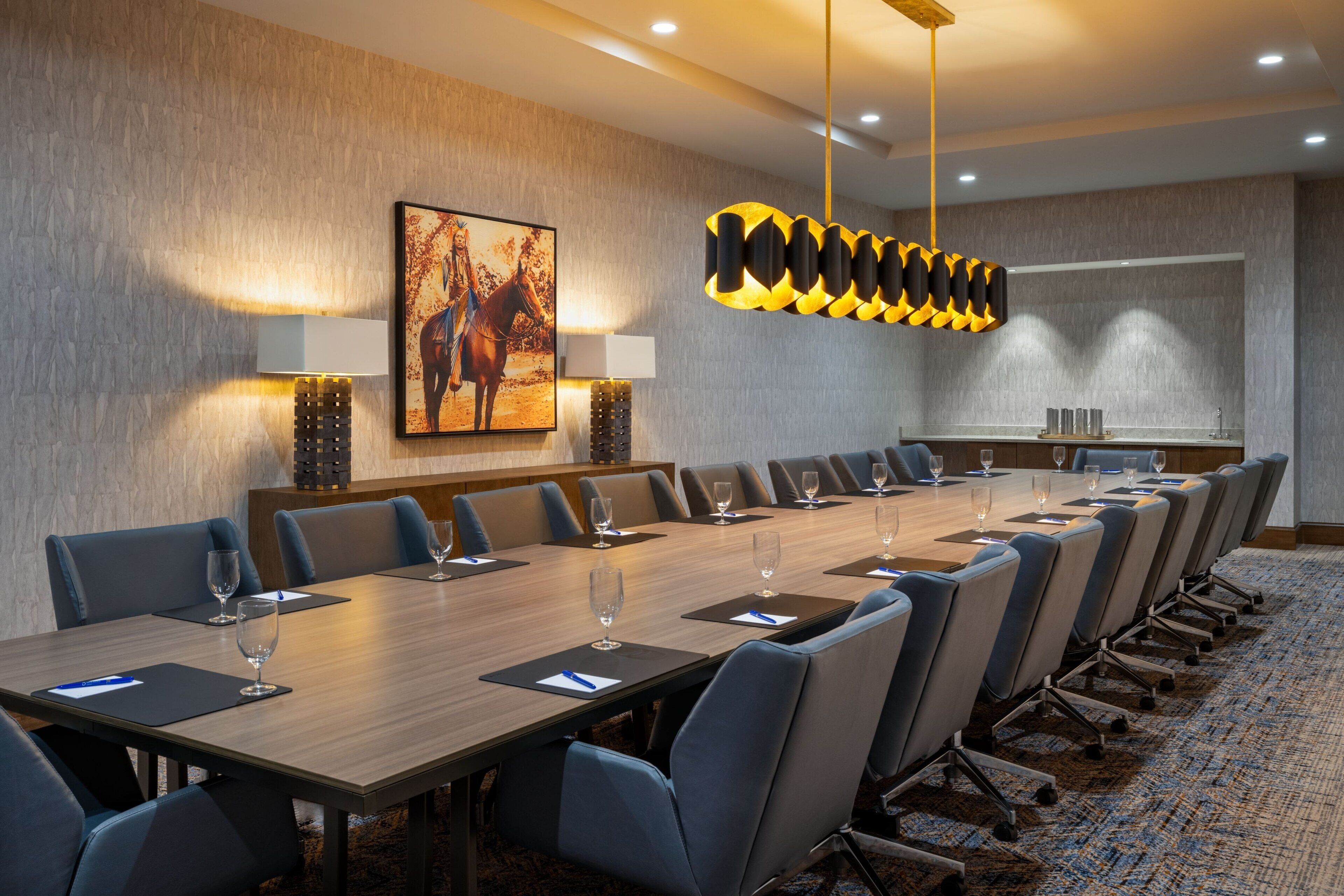 A conference room with a long table, chairs, and a painting on the wall.