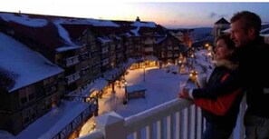 Experience the serene beauty of a snow-covered town from your balcony, overlooking the charming architecture of the surrounding buildings.