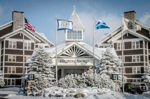 Traditional hotel with a gabled roof and central tower, surrounded by snow-covered trees.