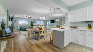Een moderne keuken met witte kastjes, een eethoek met houten stoelen en een groot eiland.