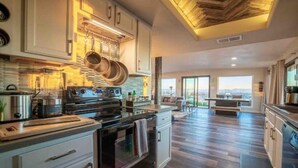 Una cocina moderna con electrodomésticos de acero inoxidable, techo de madera y un ventanal con vistas panorámicas.