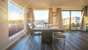 Un comedor amplio con una gran mesa, sillas y vistas de la ciudad a través de amplias ventanas.
