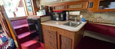 A compact kitchenette with a microwave, sink, and storage cabinets.