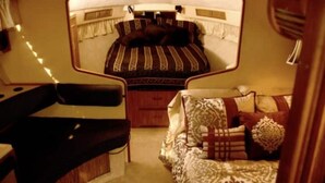 Interior compacto de una autocaravana con cama, sofá y una pequeña mesa.