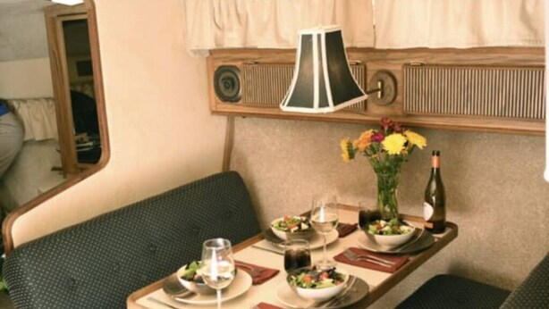 Comedor con una mesa dispuesta para dos personas, un florero con flores y una botella de vino.