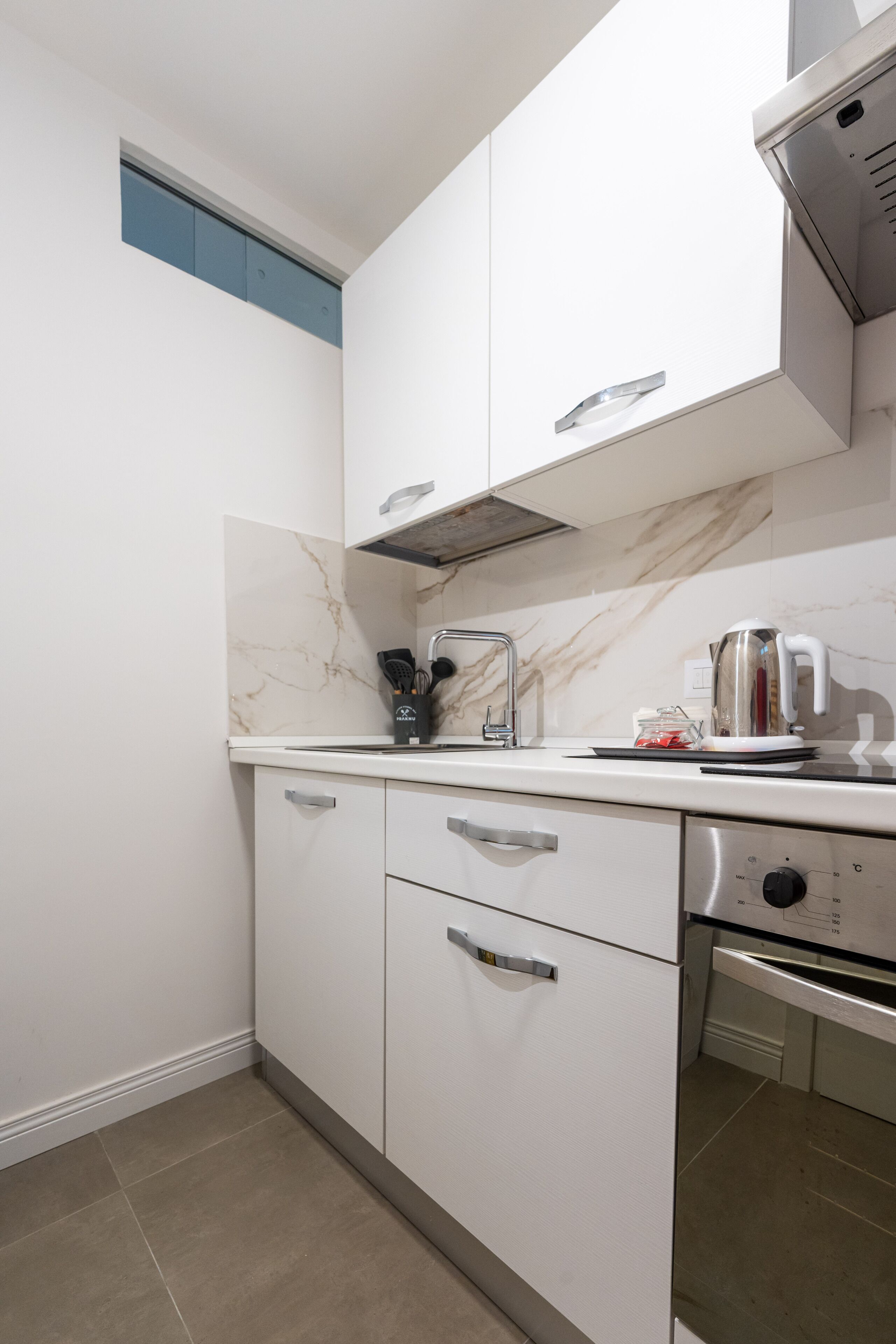 Eine Küche mit weißen Schränken, einem Edelstahlbackofen und einer Marmor-Spritzschutzwand.