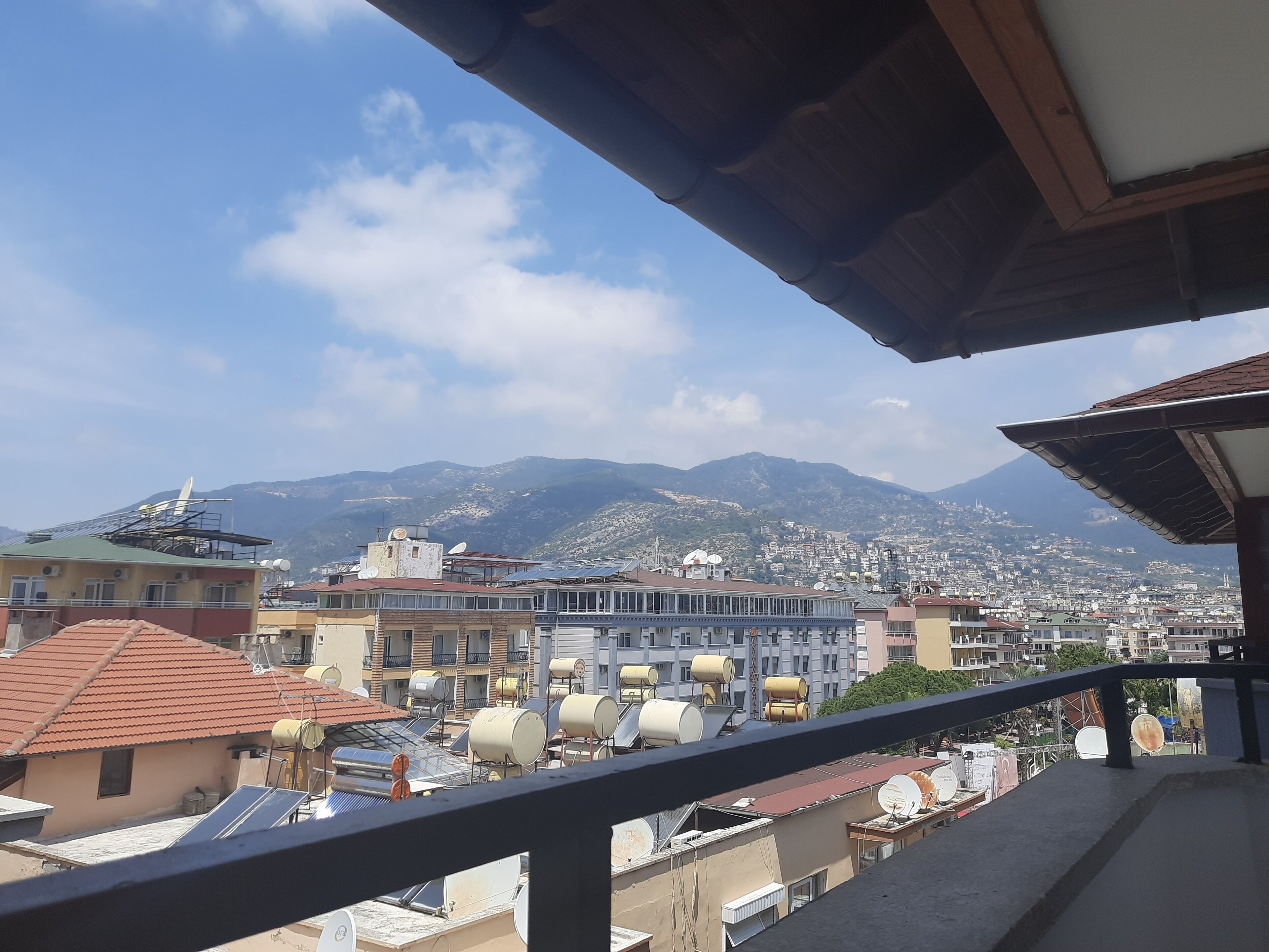 A balcony with a view of a cityscape, including buildings and mountains in the background.