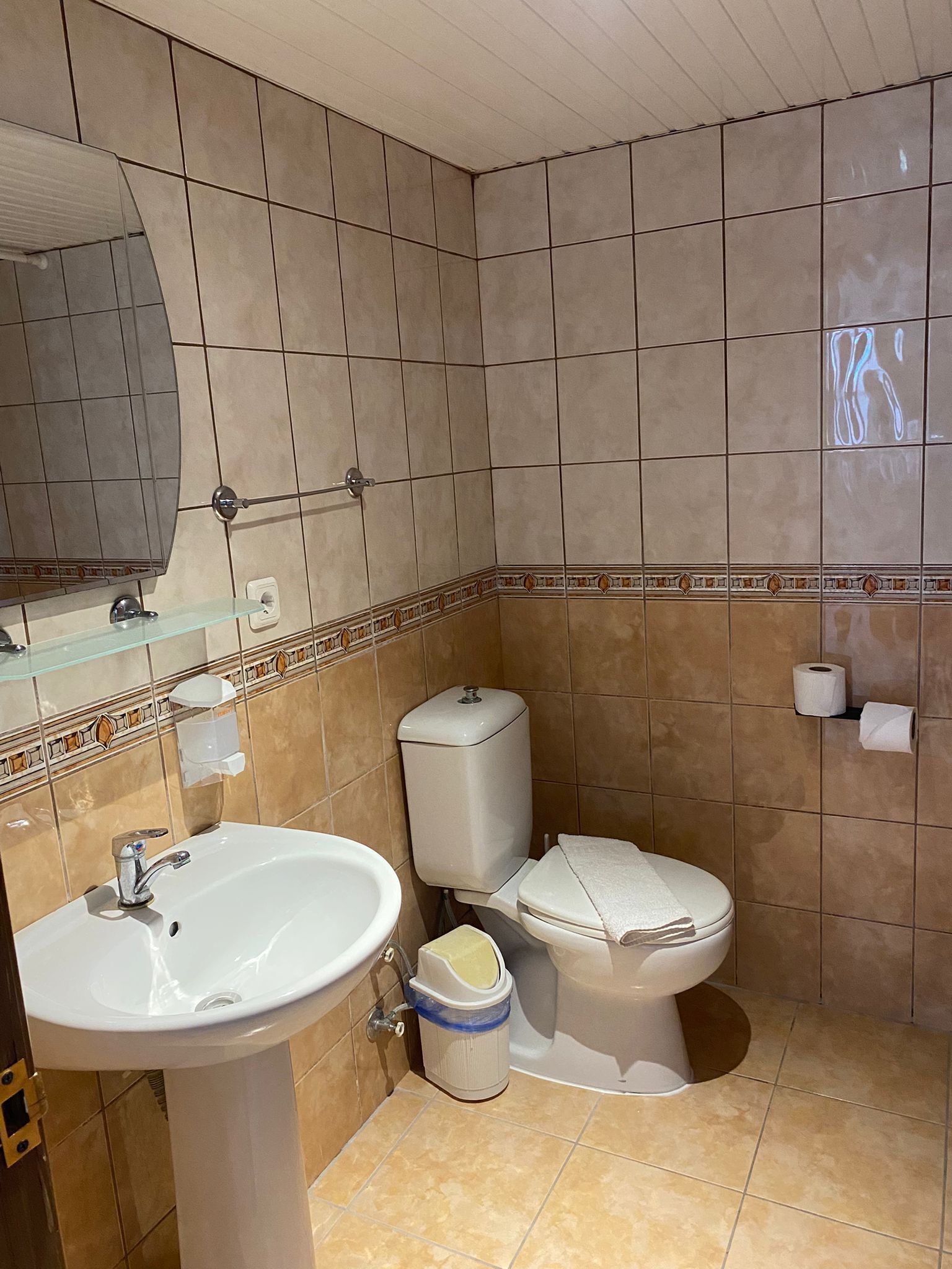 A bathroom with a sink, toilet, and mirror.