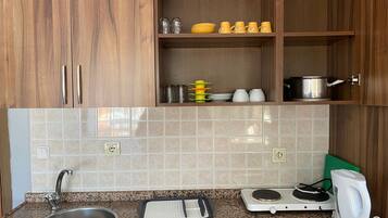Une cuisine avec des meubles en bois, un plan de travail en granit, un évier, une bouilloire, un cuiseur à riz et un grille-pain.