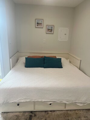 A bedroom with a bed, two framed pictures on the wall, and a white door. - Cozy Guest Suite in Edgemont Village (North Vancouver)