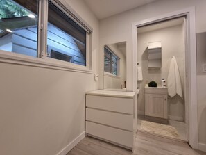 A modern bathroom with a vanity, a mirror, a towel rack, and a shower area. - Cozy Guest Suite in Edgemont Village (North Vancouver)
