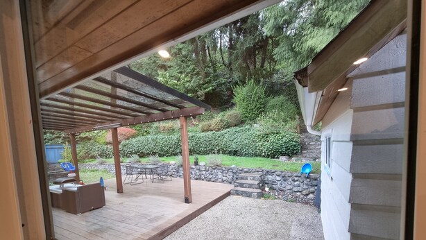 Un  área de patio techada con una pérgola, una parrilla de barbacoa y un conjunto de asientos.