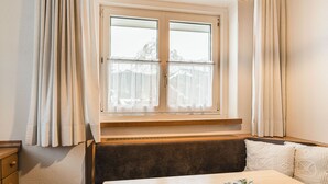 Una habitación con ventana, un banco, una mesa y una planta.