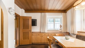 Un comedor de madera con una mesa, sillas y un televisor montado en la pared.