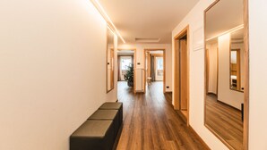 Ein Korridor mit Holzboden, einer Bank und einem großen Spiegel auf der rechten Seite.