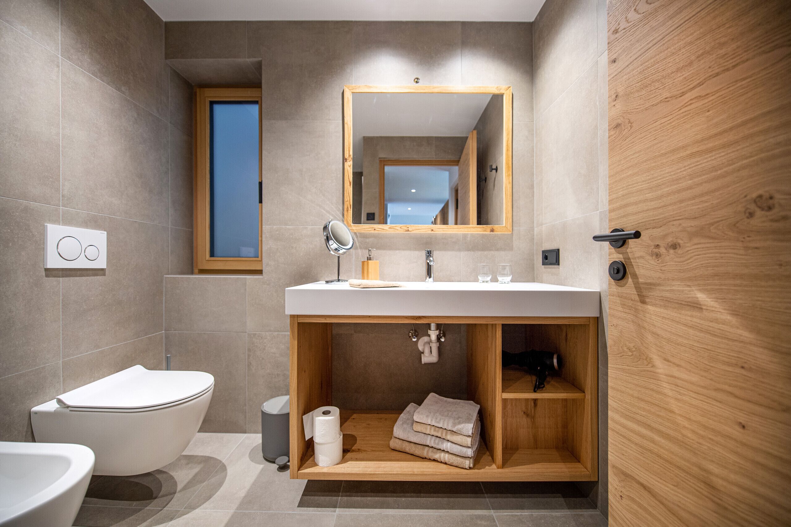 Une salle de bain moderne avec une baignoire sur pieds, un meuble-lavabo avec un miroir et une étagère en bois sous le lavabo.