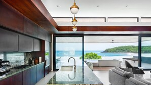 A modern kitchen with a large island, a dining area with a view of the ocean, and a cozy seating area. - Brand New Beach front 5 bedroom house steps from the beach  (San Juan del Sur)