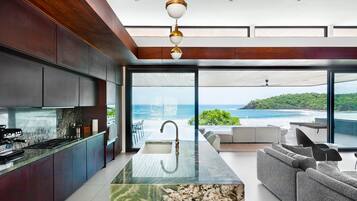 A modern kitchen with a large island, a dining area with a view of the ocean, and a cozy seating area.