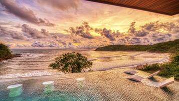 An infinity pool with a view of the ocean and a sunset.