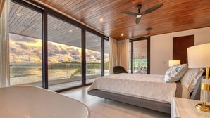 A modern bedroom with a large bed, a bathtub, and a view of the sea. - Brand New Beach front 5 bedroom house steps from the beach  (San Juan del Sur)