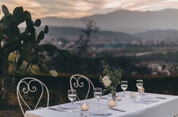 Una mesa dispuesta para una comida con vistas a un paisaje urbano y montañas al fondo.