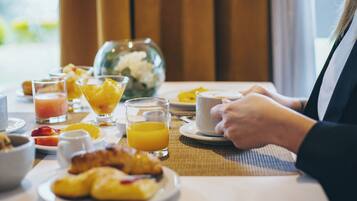 A breakfast setting with croissants, orange juice, and a fruit bowl on a table.