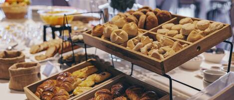 A buffet with various baked goods including pastries and bread.