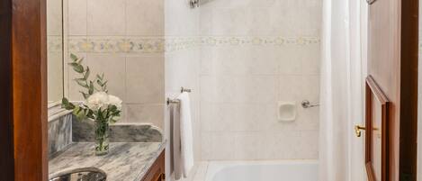 A bathroom with a marble sink, a bathtub, and a shower area.