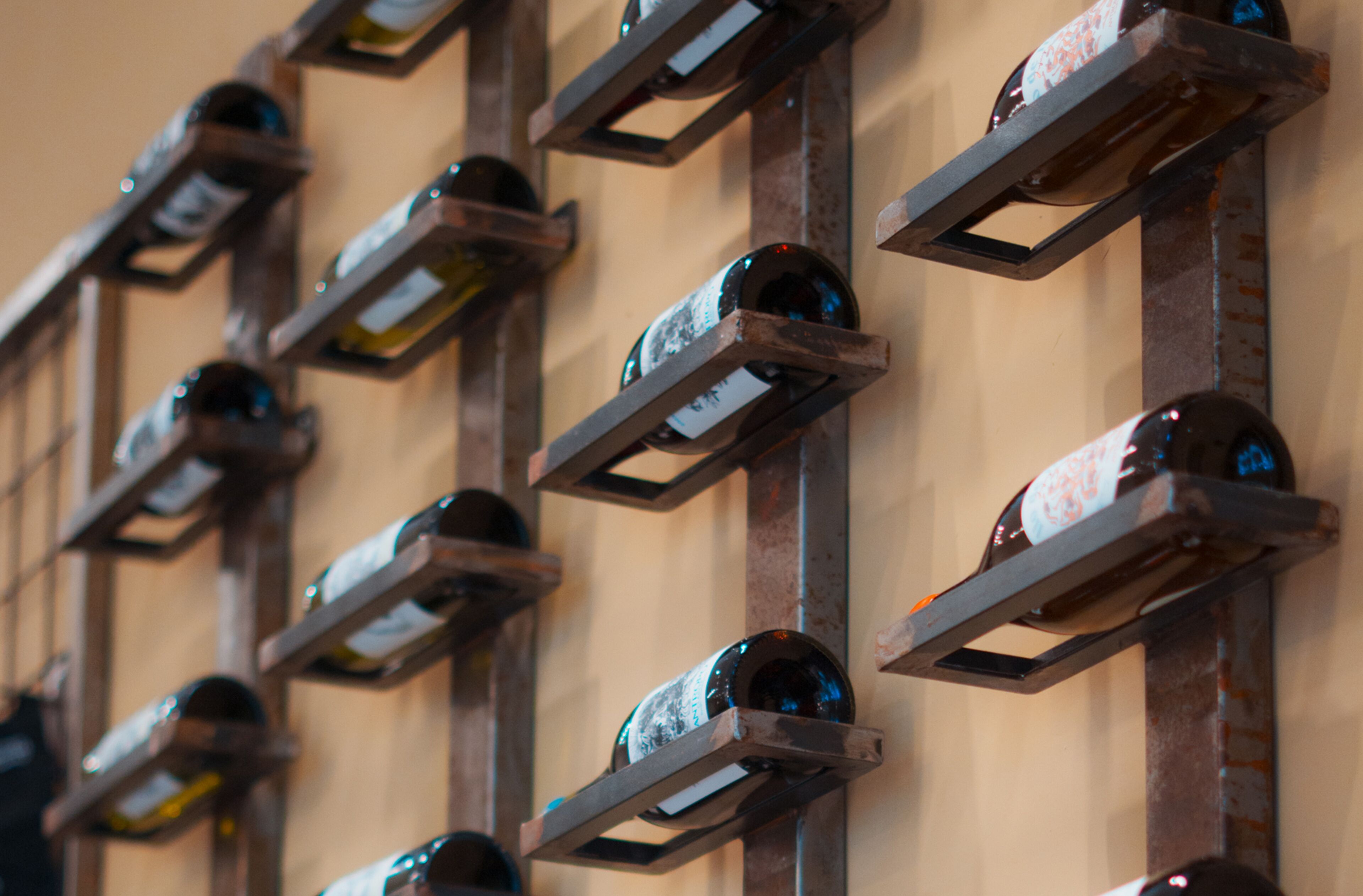 A wall of wine bottles arranged in a grid pattern on metal racks.