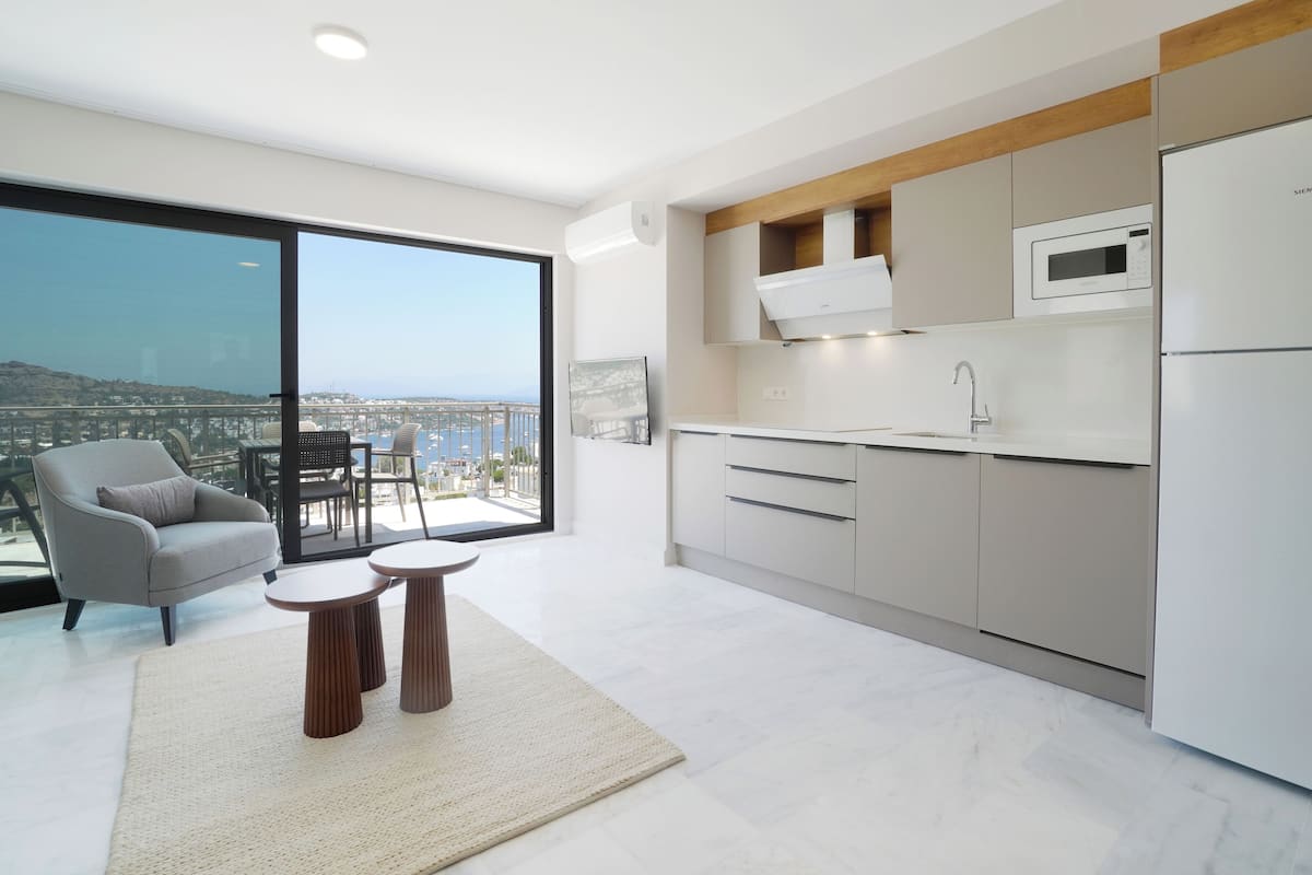 Cozinha moderna com vista para a cidade, uma poltrona cinza e uma pequena mesa.