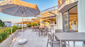 A rooftop patio with outdoor seating, a bar, and a view of the surrounding landscape. - Olira Türkbükü Residences (Bodrum)