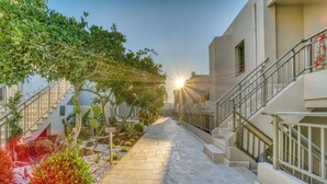 A pathway leading to a building with a staircase and a sunlit garden area. - Olira Türkbükü Residences (Bodrum)