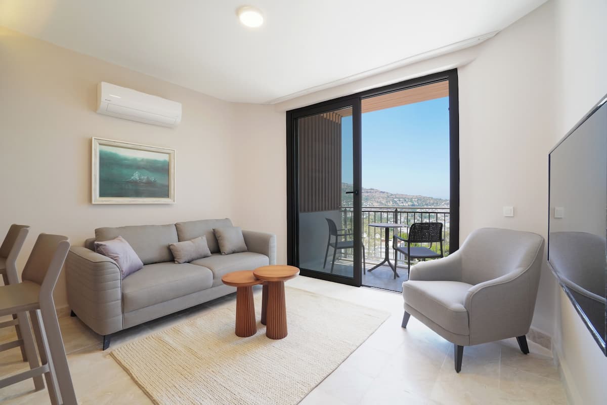 Uma sala de estar moderna com um sofá, poltronas, uma mesinha de centro e uma televisão.