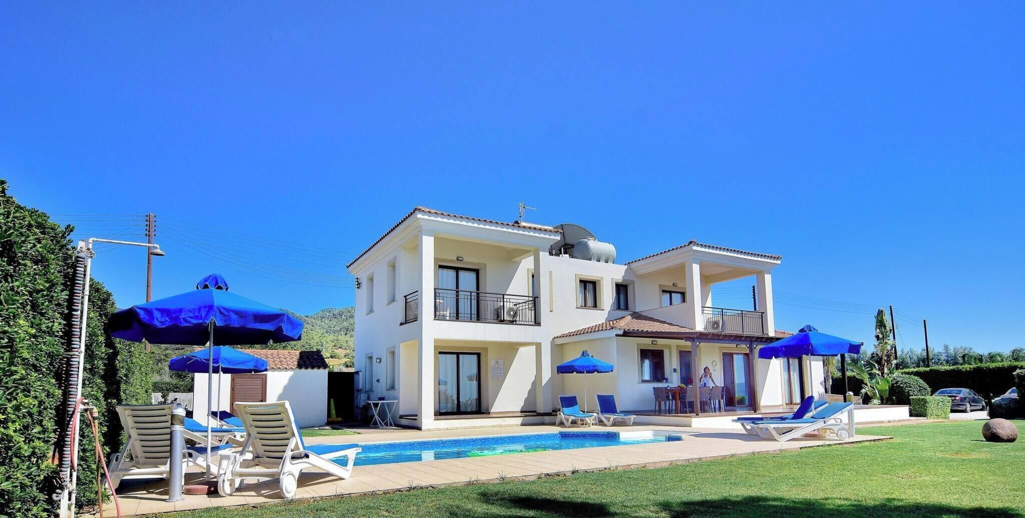 A two-story building with a swimming pool, outdoor seating, and umbrellas.