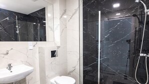 Une salle de bain moderne avec un lavabo en marbre, des toilettes et une douche séparée par une paroi de verre.