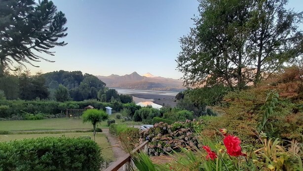 Un sendero de jardín que lleva a un mirador con vistas a un lago y montañas distantes.