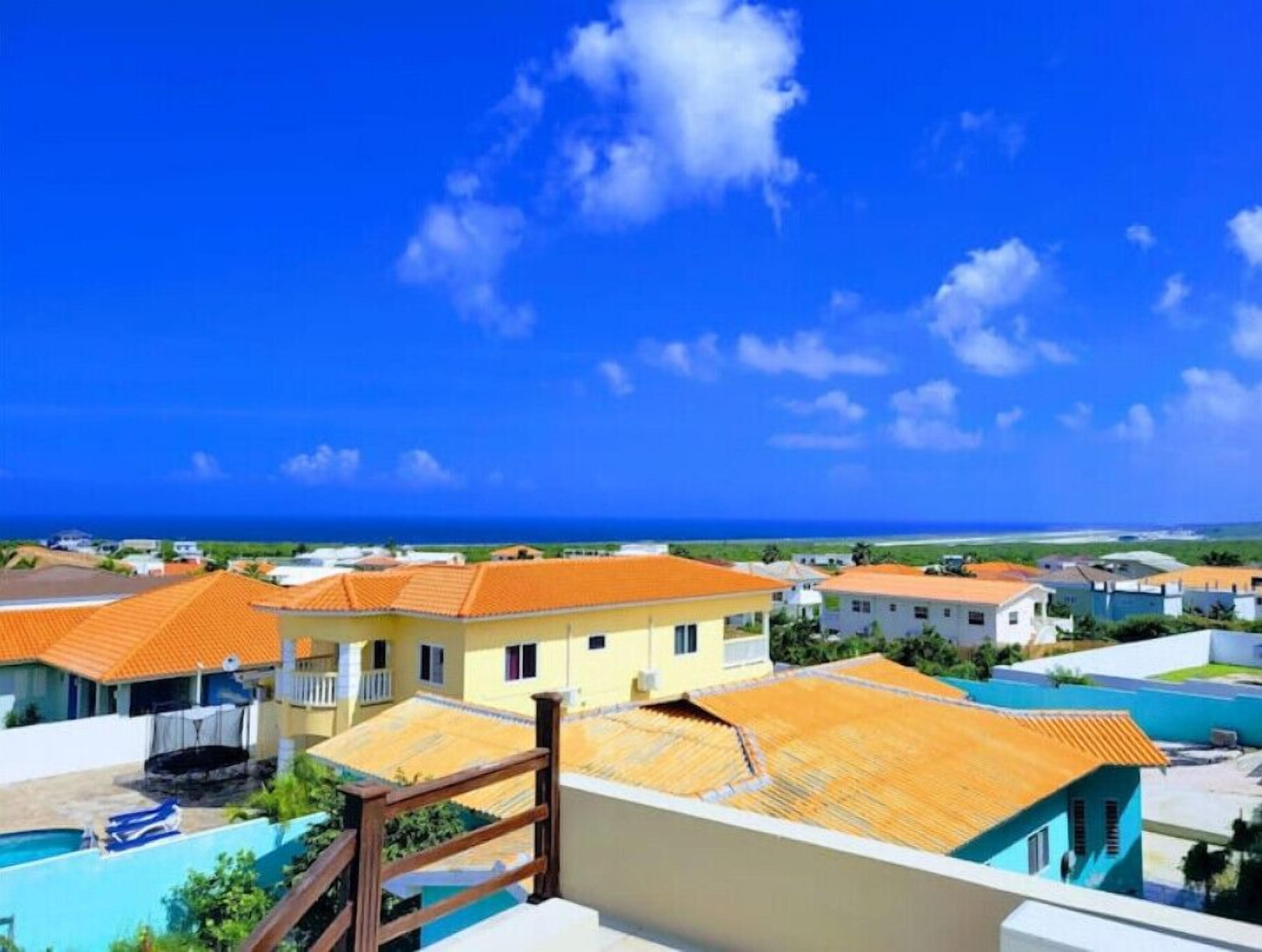 A coastal residential area with houses featuring orange roofs and a clear blue sky.