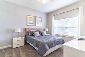 A bedroom with a bed, nightstands, a desk, and a window with blinds.