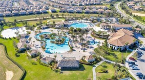 An aerial view of a resort with multiple swimming pools, a large central pool, and a clubhouse.