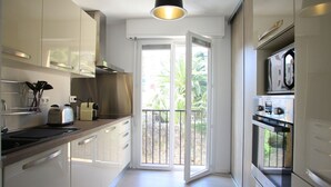 A modern kitchen with stainless steel appliances, a toaster, and a hanging utensil rack. - Centru : Appart lumineux vue mer, 5 min à pied de la plage et du centre (Calvi)